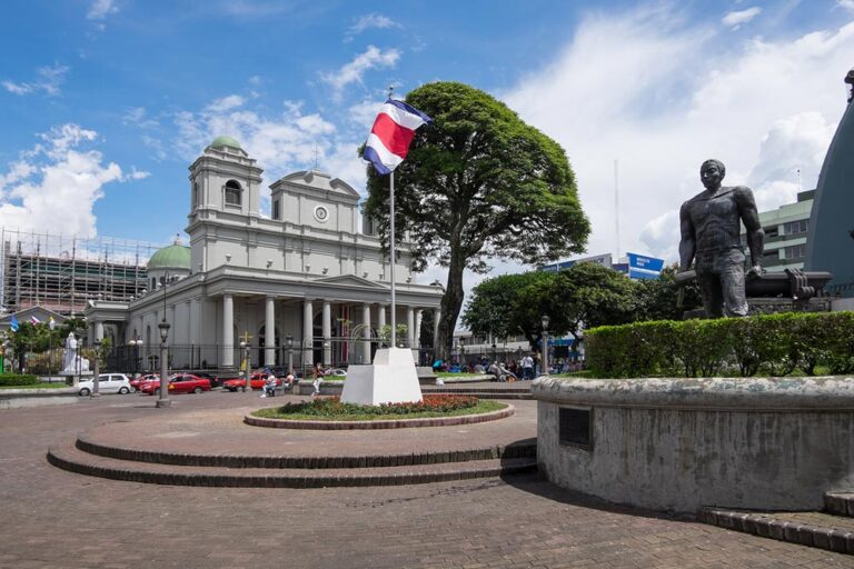 historic building in costa rica with a statue and a flag in front of it