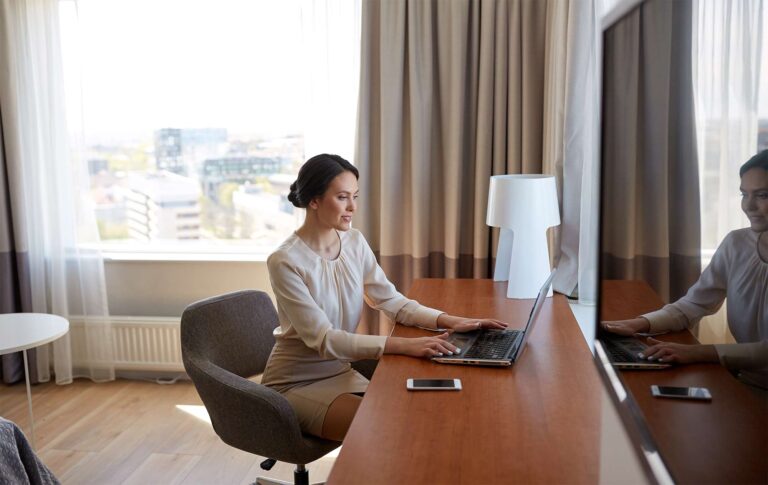 woman sitting at a desk in a hotel room working