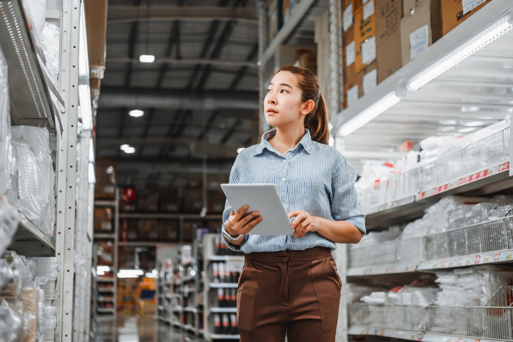 Asian woman worker working with digital tablet checking boxes Logistic import and export supplies packages in Warehouse , Logistics concept